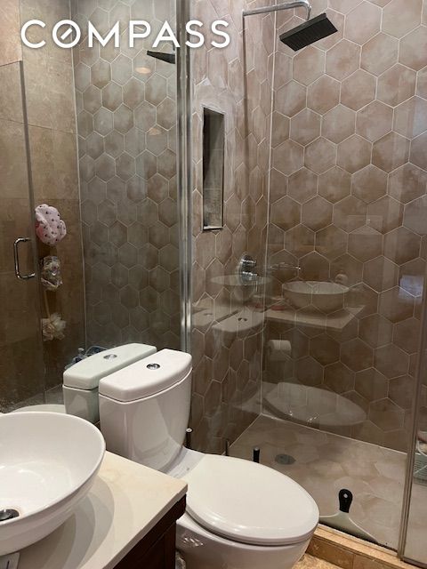 bathroom with a shower stall, toilet, and vanity