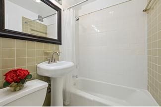 bathroom with decorative backsplash, bathing tub / shower combination, tile walls, and toilet