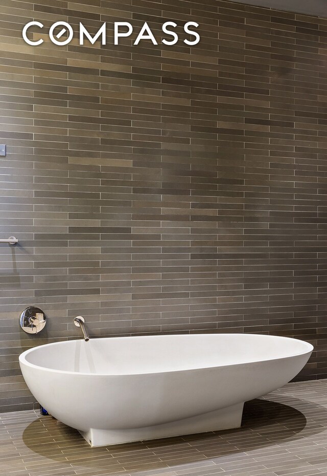 full bathroom featuring a freestanding bath and tile walls