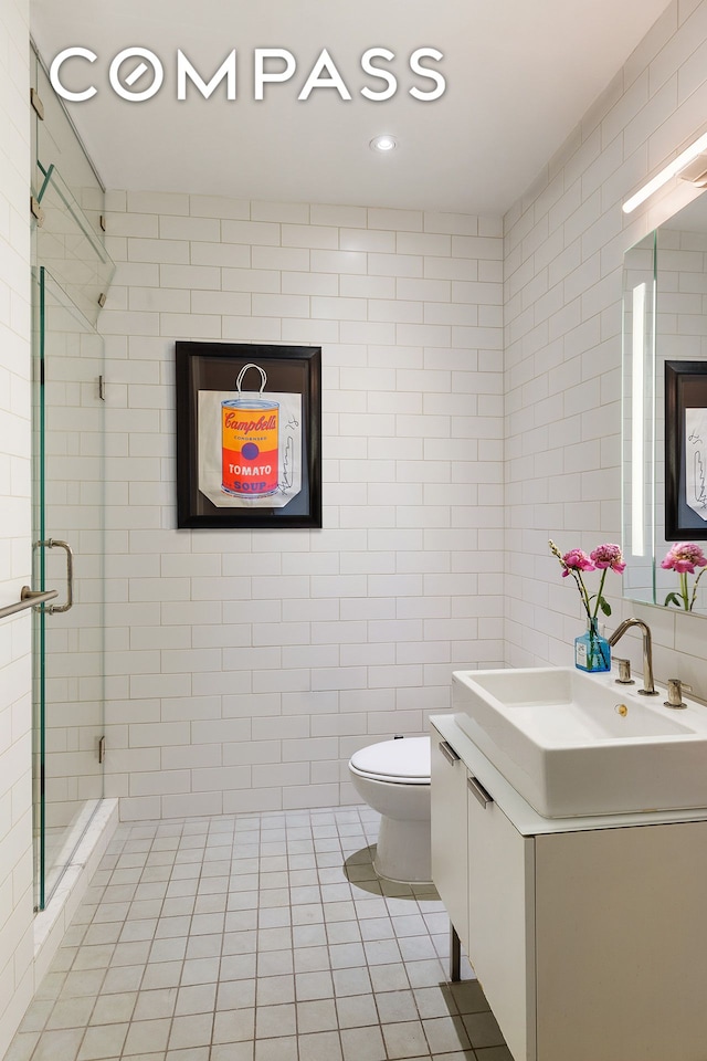 bathroom featuring toilet, vanity, tile walls, a shower stall, and tile patterned floors