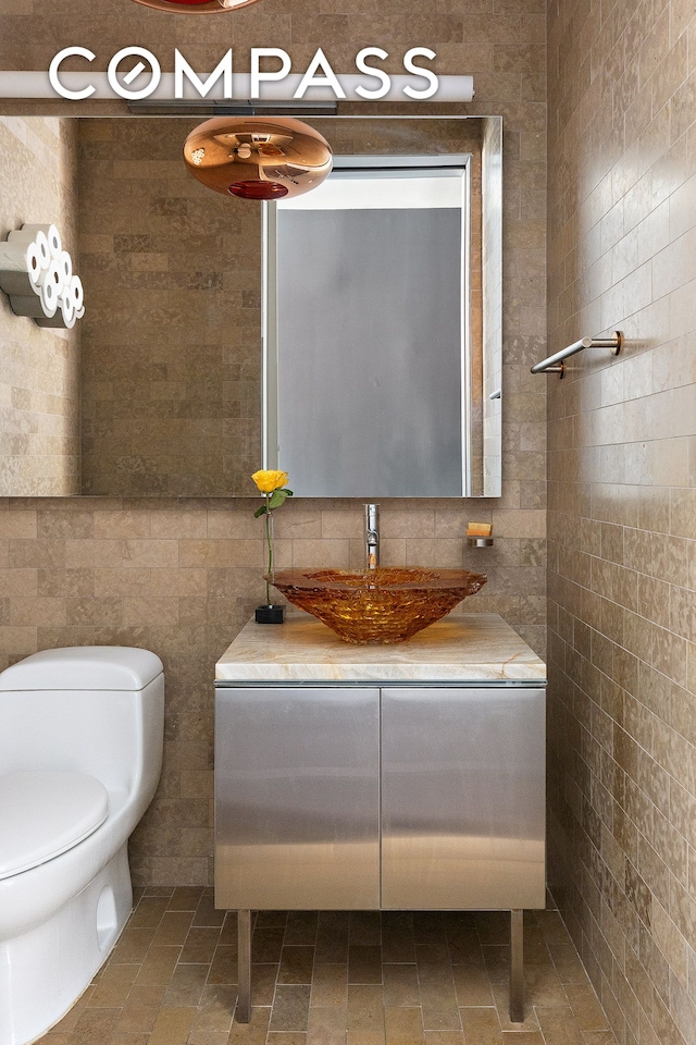 bathroom featuring decorative backsplash, toilet, tile walls, and vanity