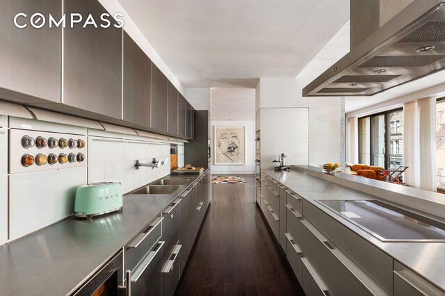 kitchen with wall chimney exhaust hood, stainless steel countertops, modern cabinets, and a sink