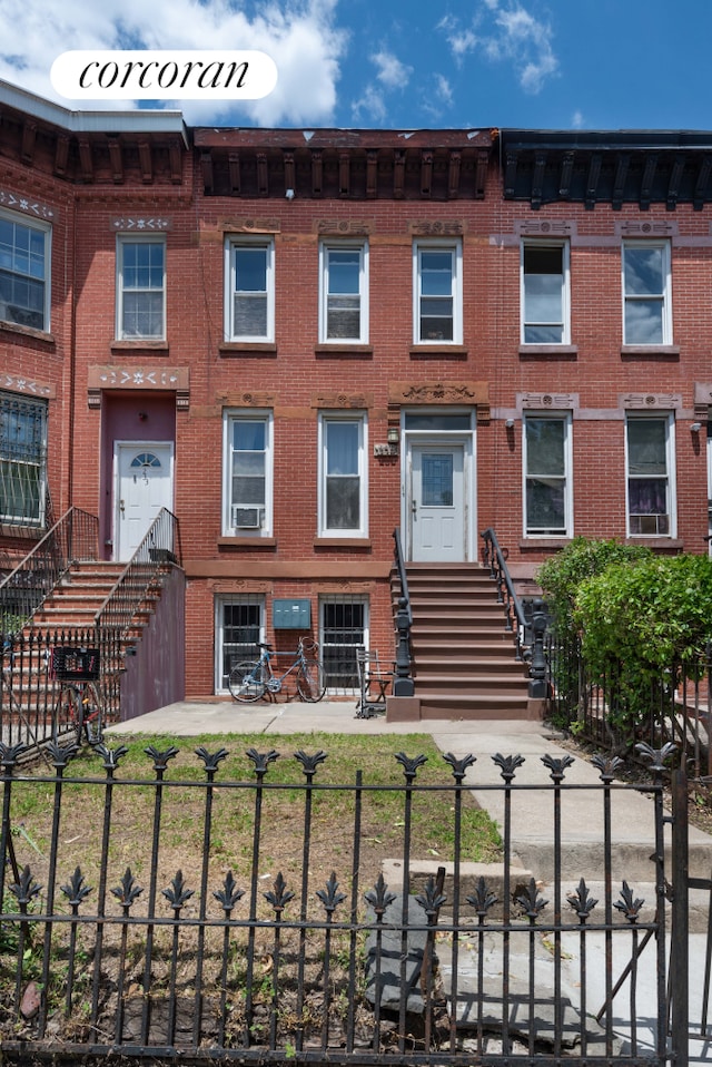 townhome / multi-family property with a fenced front yard and brick siding