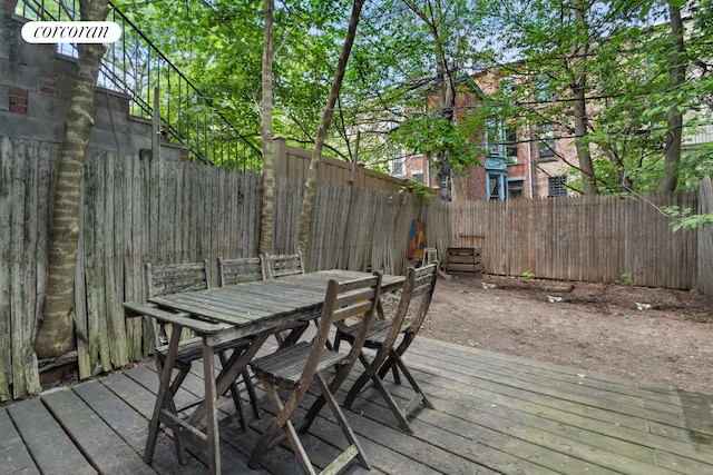 wooden terrace with outdoor dining space and a fenced backyard