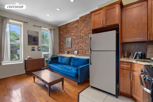 kitchen with visible vents, freestanding refrigerator, brown cabinets, gas range, and crown molding