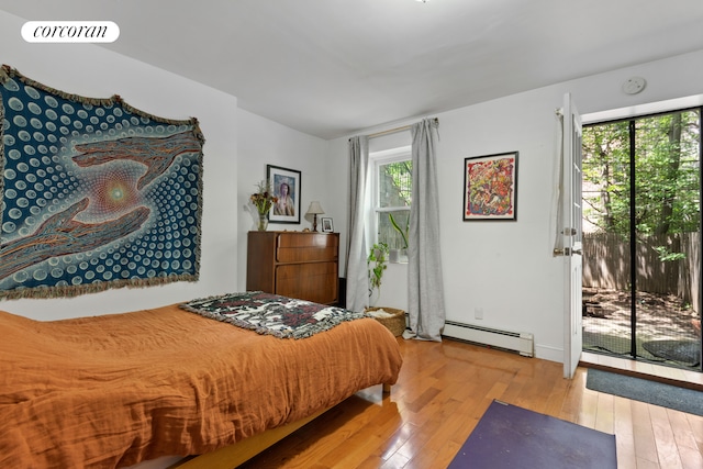 bedroom featuring access to exterior, wood-type flooring, visible vents, and a baseboard heating unit