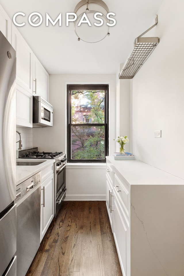 kitchen with baseboards, stainless steel appliances, decorative backsplash, dark wood-type flooring, and white cabinets