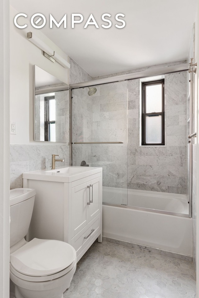 bathroom featuring enclosed tub / shower combo, toilet, tile walls, and vanity