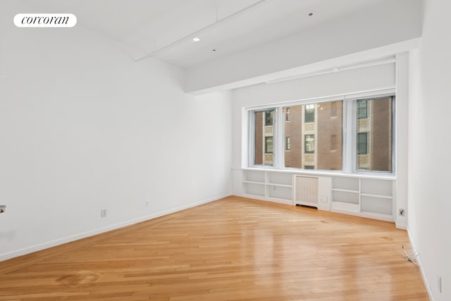 empty room with light wood finished floors, visible vents, radiator, and baseboards