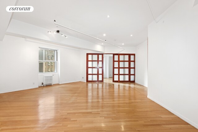 spare room featuring radiator, light wood-type flooring, baseboards, and recessed lighting