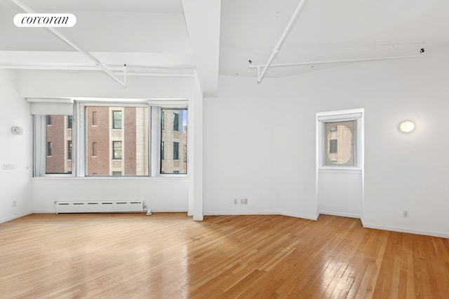 empty room featuring a baseboard heating unit, baseboards, visible vents, and hardwood / wood-style floors