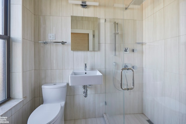 full bathroom with toilet, a stall shower, tile walls, and a sink