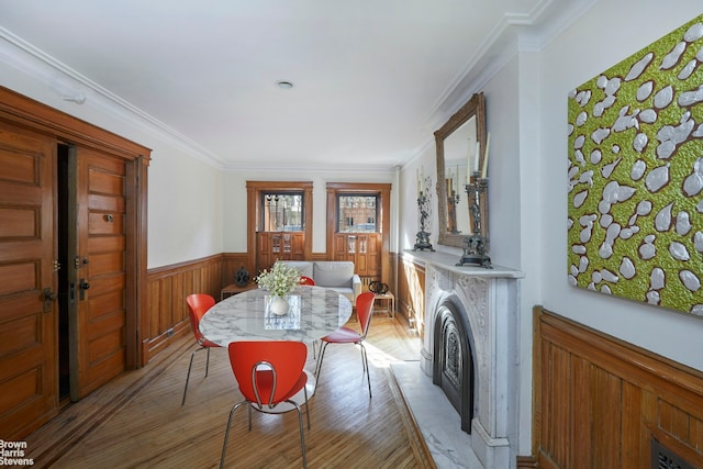 dining space with ornamental molding, wood finished floors, and wainscoting