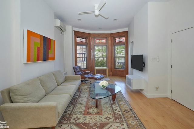 living room featuring ceiling fan, a wall unit AC, light wood-style flooring, recessed lighting, and baseboards