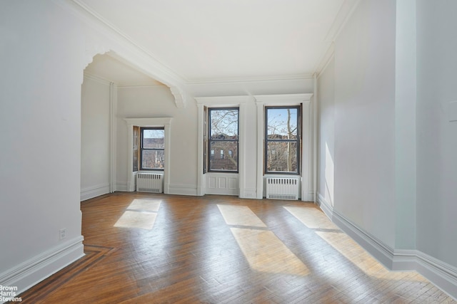 unfurnished room featuring radiator heating unit, wood finished floors, and crown molding