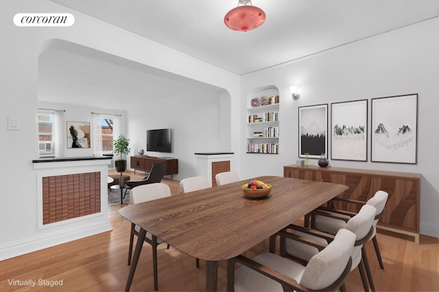 dining room featuring built in shelves, light wood-type flooring, visible vents, and baseboards