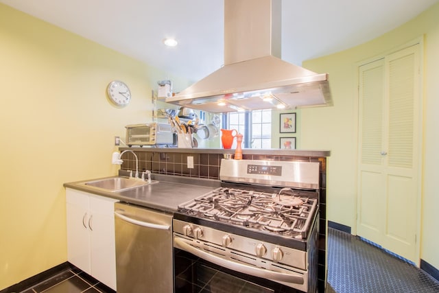 kitchen with island exhaust hood, a sink, white cabinets, appliances with stainless steel finishes, and backsplash