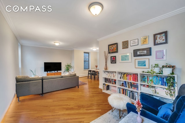 living area with baseboards, baseboard heating, light wood-style flooring, and ornamental molding