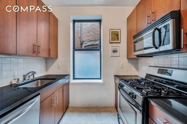 120 2nd Ave Unit 5A, New York City, NY 10003 - kitchen with appliances with stainless steel finishes, brown cabinets, tasteful backsplash, and dark stone countertops
