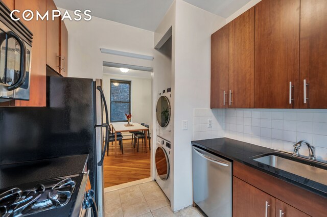 120 2nd Ave Unit 5A, New York City, NY 10003 - kitchen featuring stainless steel appliances, stacked washer / drying machine, decorative backsplash, a sink, and light tile patterned flooring