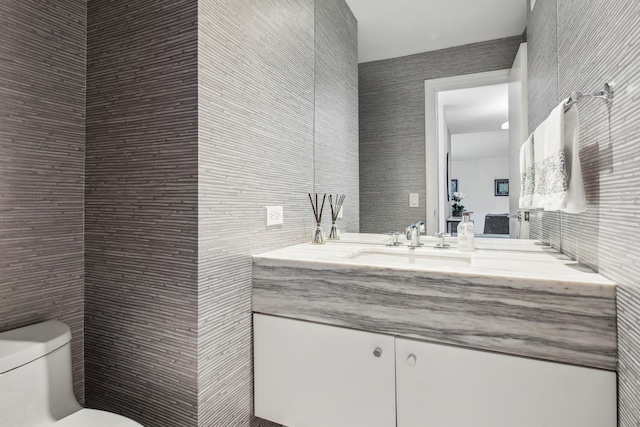 bathroom with tile walls, toilet, and vanity