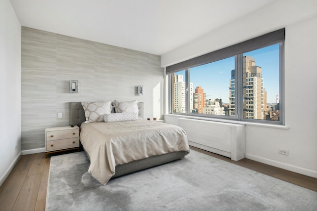 200 E 62nd St Unit 23D, New York City, NY 10065 - bedroom featuring a skyline view, baseboards, and hardwood / wood-style flooring