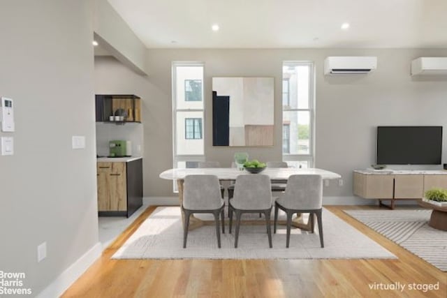 dining space featuring an AC wall unit, a wall mounted air conditioner, light wood-type flooring, and baseboards