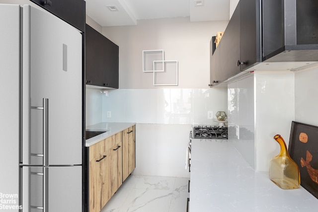 kitchen with built in refrigerator, light countertops, stainless steel gas stovetop, marble finish floor, and modern cabinets