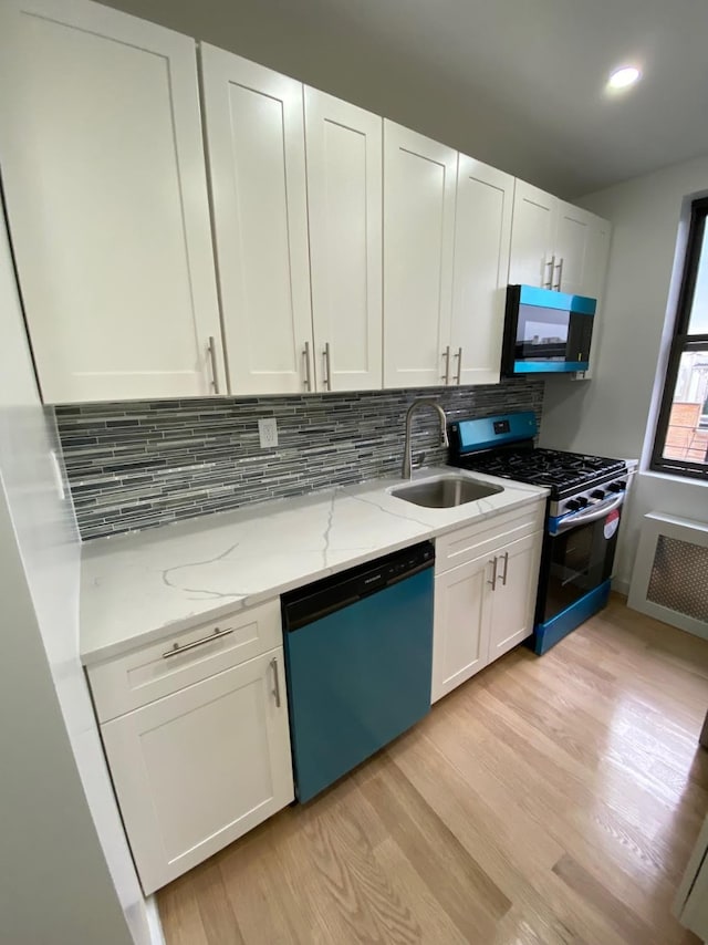 kitchen featuring black microwave, dishwashing machine, a sink, radiator, and gas range