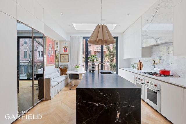 kitchen featuring stainless steel appliances, a skylight, a sink, white cabinets, and modern cabinets