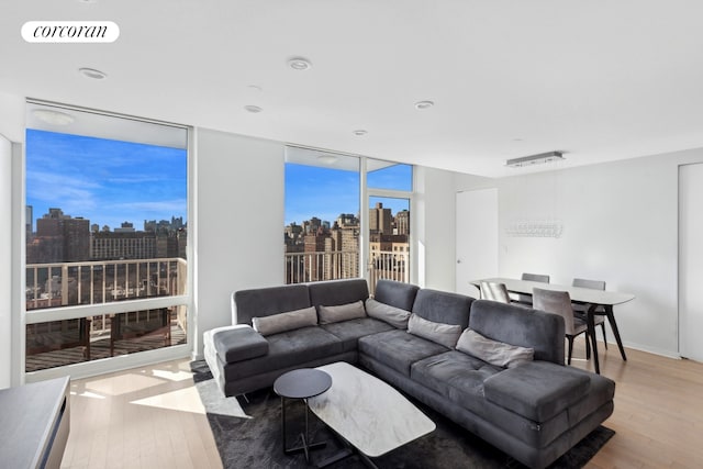 living room with light wood-style floors, a view of city, floor to ceiling windows, and visible vents