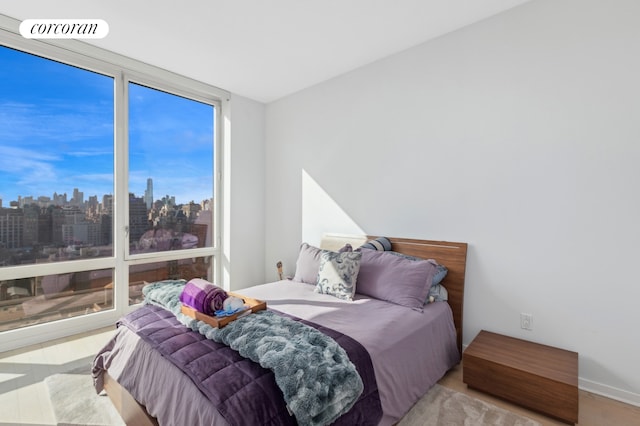 bedroom with visible vents, a city view, wood finished floors, and a wall of windows
