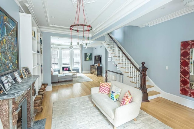 living area with crown molding, stairway, and wood finished floors