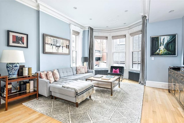 living room featuring radiator, light wood-type flooring, ornamental molding, and baseboards