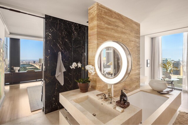 53 W 53rd St Unit 49A, New York City, NY 10019 - bathroom featuring a city view, a sink, a bathtub, and a wall of windows