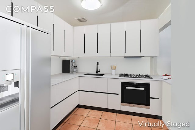 kitchen with fridge with ice dispenser, a sink, black oven, white cabinets, and light countertops