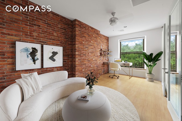 living room with brick wall, ceiling fan, and wood finished floors