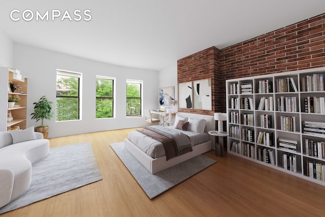 bedroom featuring brick wall and wood finished floors