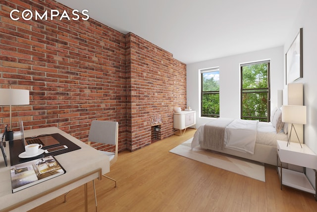 bedroom with brick wall, a brick fireplace, and wood finished floors