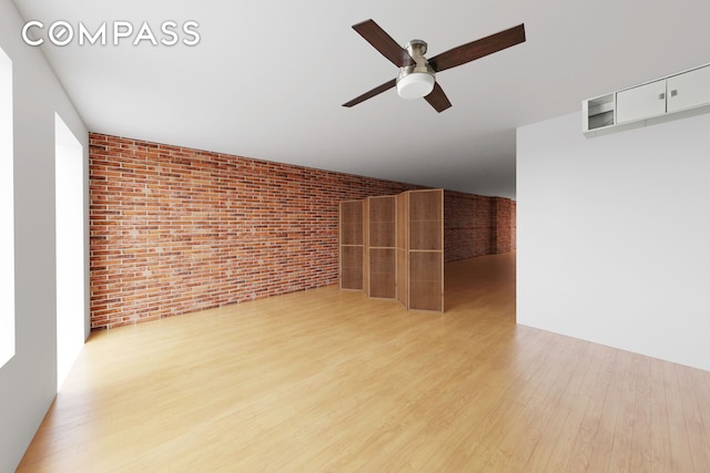 spare room featuring ceiling fan, brick wall, and wood finished floors