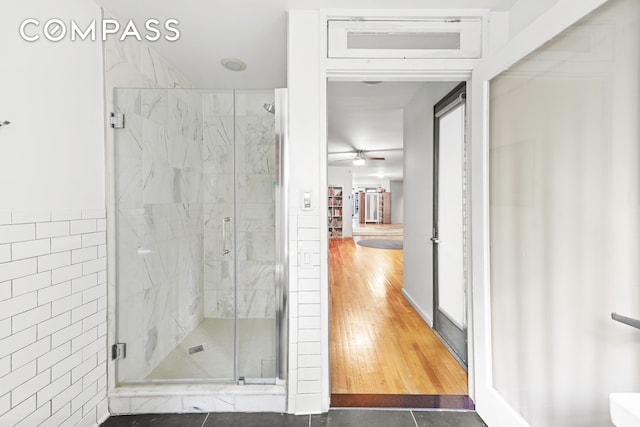 full bath with ceiling fan, tile patterned flooring, a marble finish shower, and tile walls