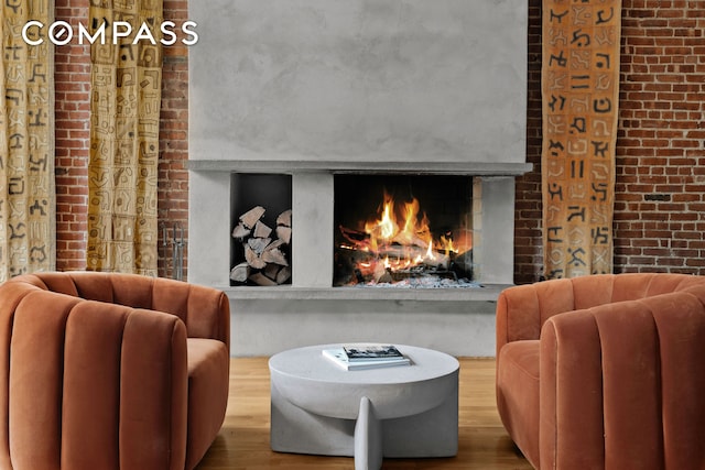 sitting room featuring brick wall, a fireplace, and wood finished floors