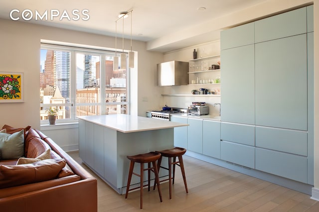 kitchen featuring light wood finished floors, a kitchen island, a kitchen breakfast bar, light countertops, and open shelves