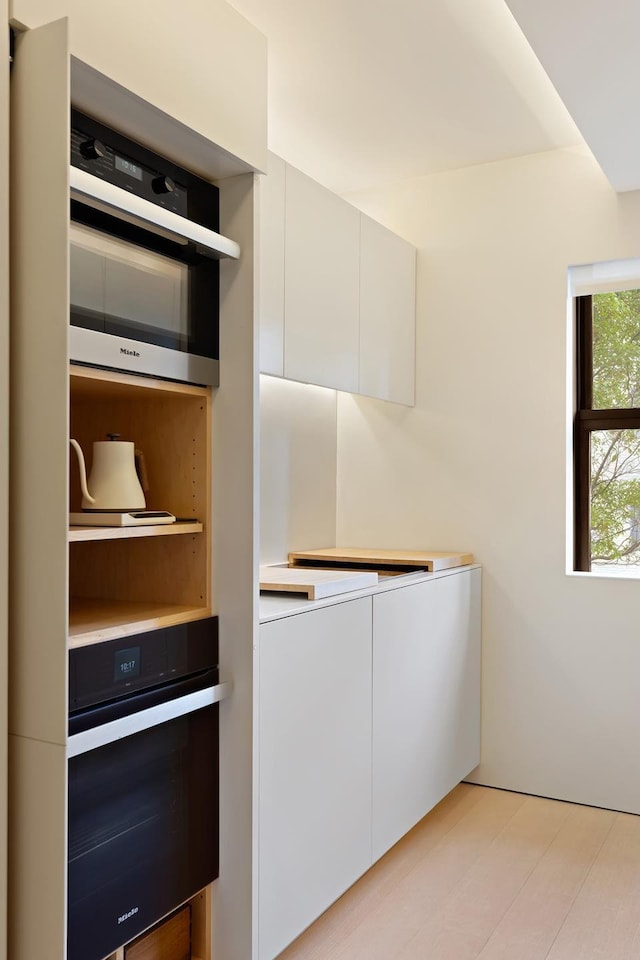 kitchen with wall oven, white cabinets, and light countertops