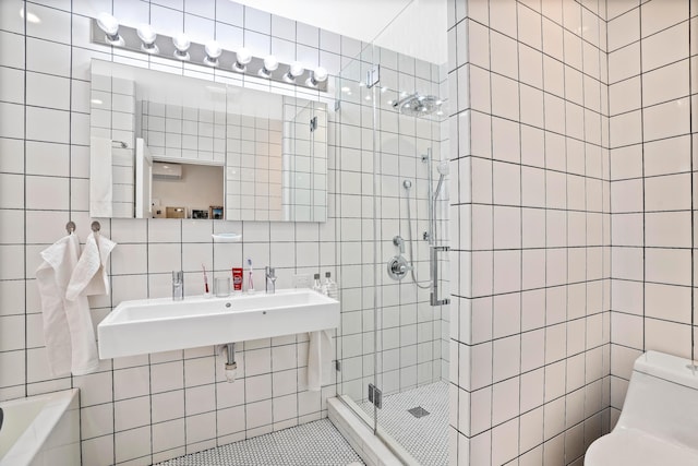 bathroom with toilet, a sink, tile walls, tasteful backsplash, and a stall shower