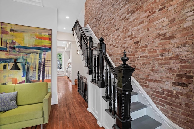 stairs with recessed lighting, baseboards, brick wall, and wood finished floors