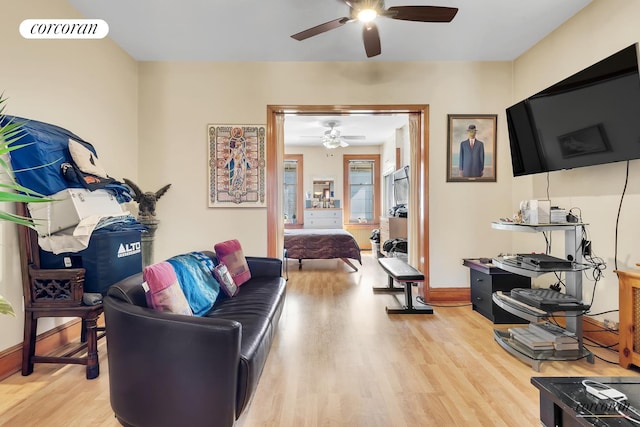 living area with ceiling fan, light wood finished floors, visible vents, and baseboards