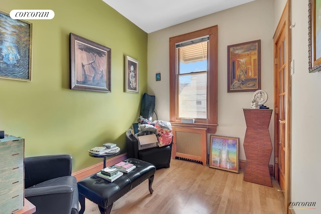 sitting room featuring visible vents, radiator heating unit, and wood finished floors