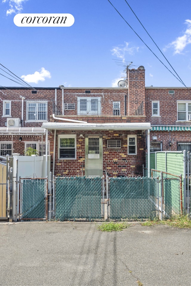 multi unit property with brick siding, a fenced front yard, and a gate