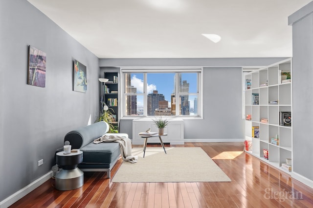 sitting room with wood-type flooring, a view of city, and baseboards